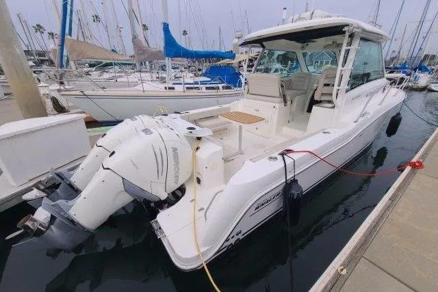 Slide: The Image of 2019 Boston Whaler 315 Conquest boat docked in marina, featuring twin outboard engines. - 6