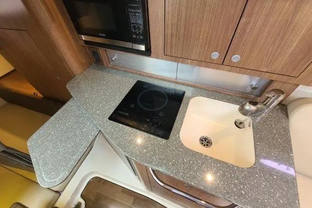 Slide: The Image of 2019 Boston Whaler 315 Conquest kitchen with stove, sink, and microwave. - 62