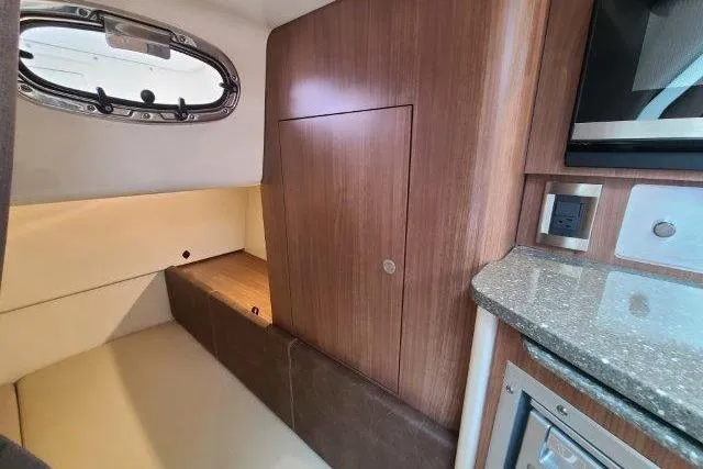 Slide: The Image of 2019 Boston Whaler 315 Conquest cabin interior with wood paneling and compact kitchenette. - 66