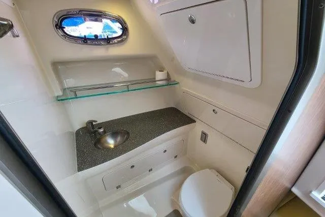 Slide: The Image of 2019 Boston Whaler 315 Conquest bathroom with sink, toilet, and porthole window. - 68