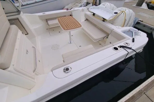Slide: The Image of 2019 Boston Whaler 315 Conquest boat interior with seating and wooden table. - 9