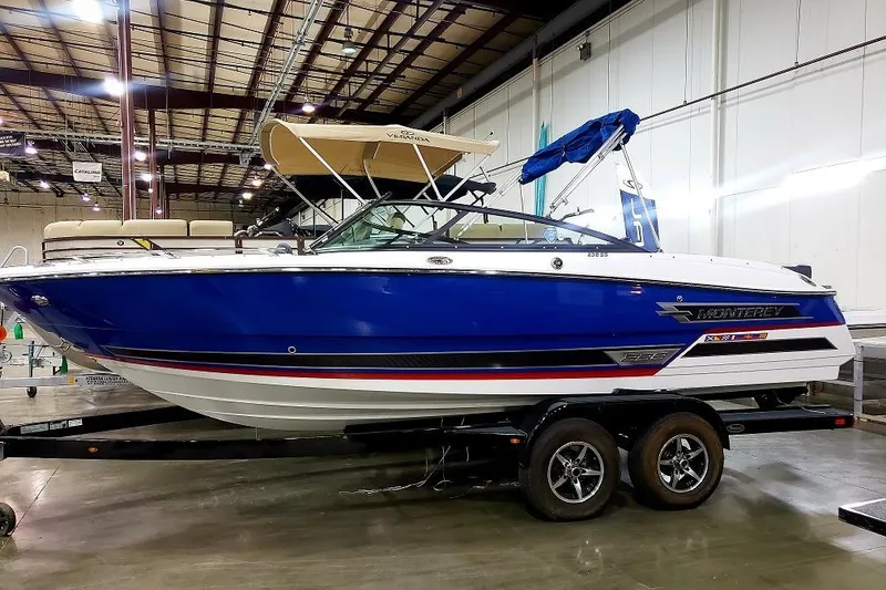 The Image of 2022 Monterey 238SS Super Sport boat in showroom, blue and white design, on trailer. - 0