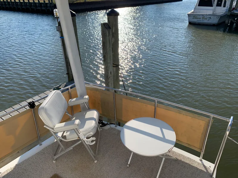 Slide: The Image of 1992 Silverton 34 Aft Cabin Motor Yacht deck with chairs and table by the water. - 24