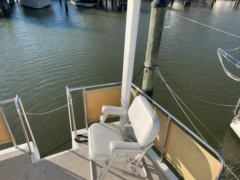 Slide: The Image of 1992 Silverton 34 Aft Cabin Motor Yacht deck with chair, overlooking marina water. - 26