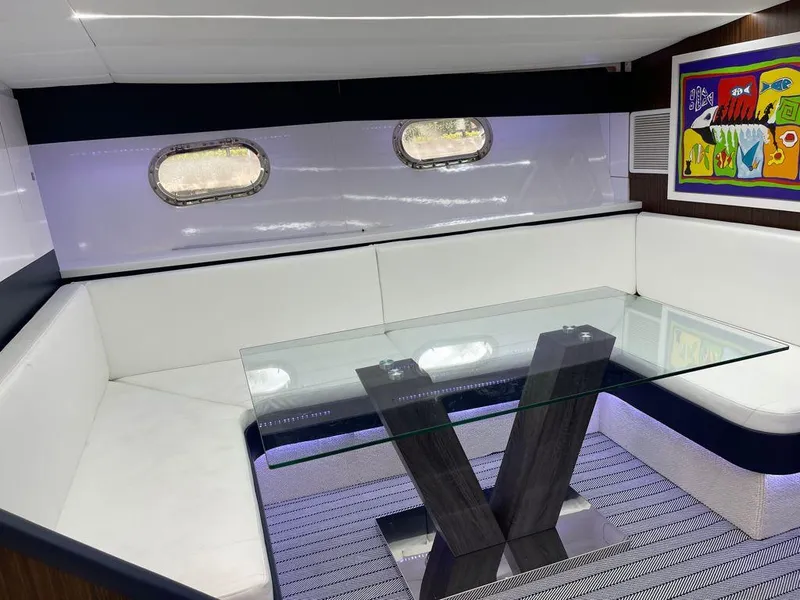 Slide: The Image of 1984 Magnum Marine interior with white seating, glass table, and colorful wall art. - 2