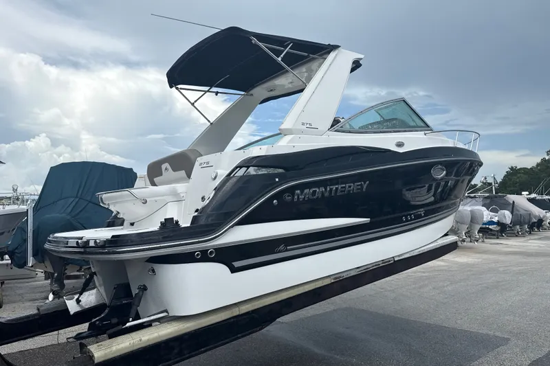 Slide: The Image of 2015 Monterey 275 Sport Yacht on trailer, sleek design, black and white exterior, marina background. - 1