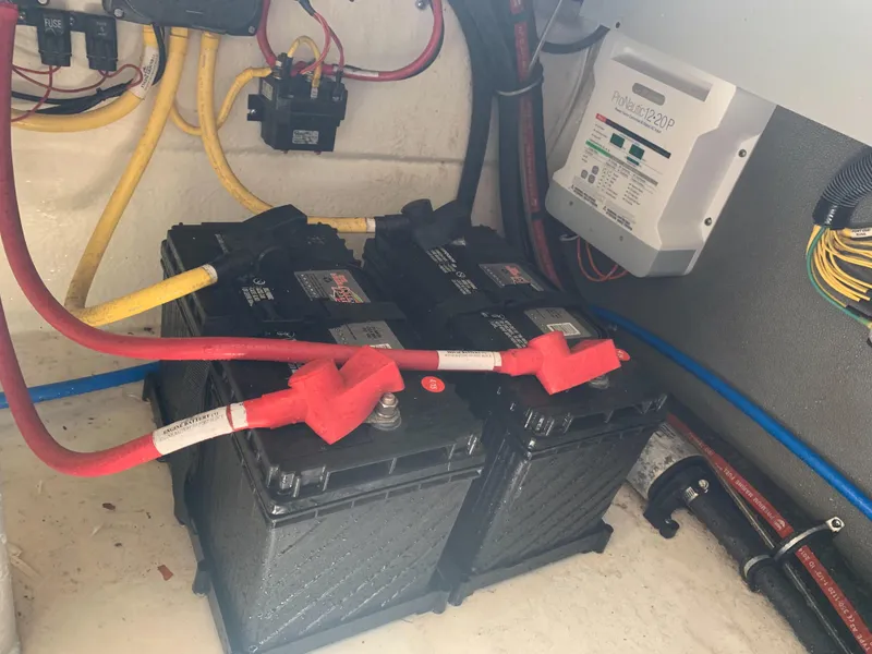 Slide: The Image of Batteries and wiring in a boat engine compartment, with a charger mounted on the wall. - 32