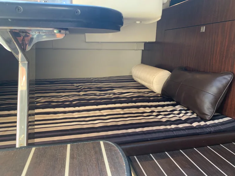 Slide: The Image of The image shows a cozy cabin with striped bedding and pillows on a 2015 Monterey 275 Sport Yacht. - 36