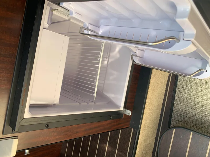 Slide: The Image of An open refrigerator in a 2015 Monterey 275 Sport Yacht, featuring wood paneling. - 16