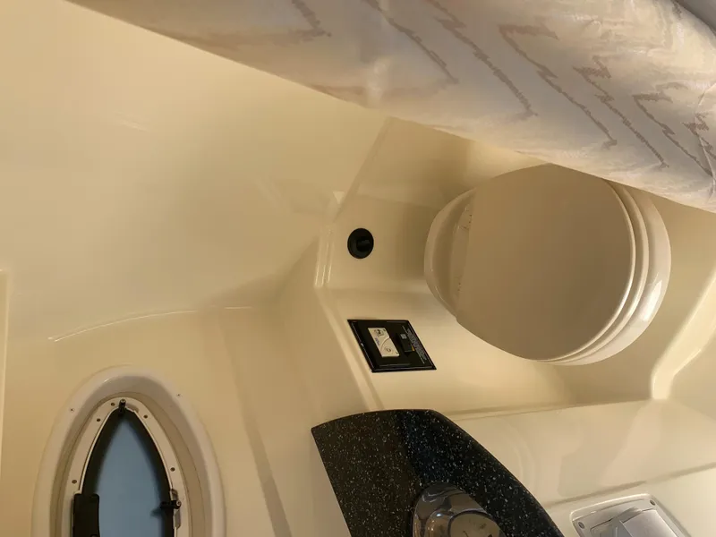 Slide: The Image of Interior of a 2015 Monterey 275 Sport Yacht with a toilet and porthole. - 43