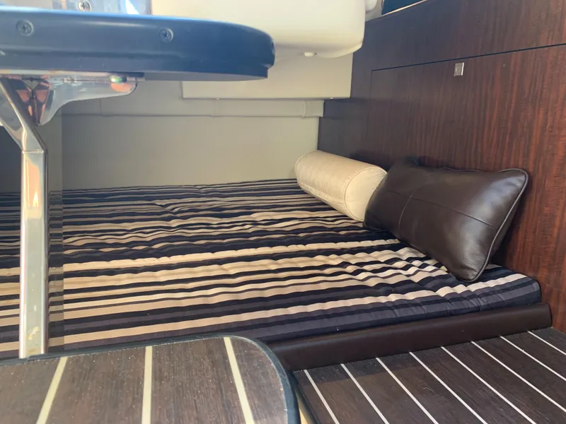 Slide: The Image of Interior of a 2015 Monterey 275 Sport Yacht with a striped bed and pillows. - 10