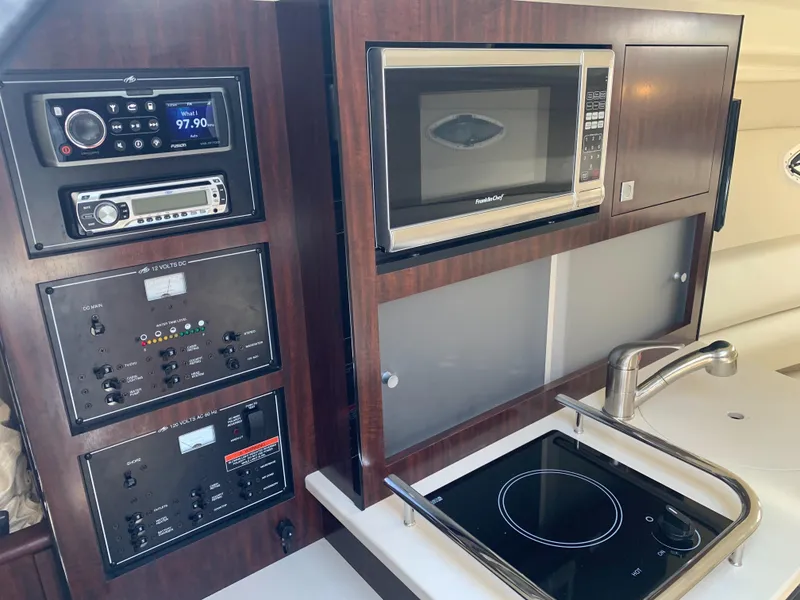 Slide: The Image of The 2015 Monterey 275 Sport Yacht's galley features a cooktop, microwave, and audio system. - 11