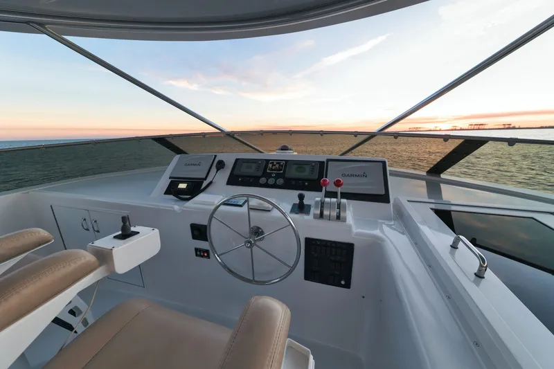 Slide: The Image of 2002 Hatteras Motor Yacht helm with sunset view, featuring modern controls and leather seating. - 14