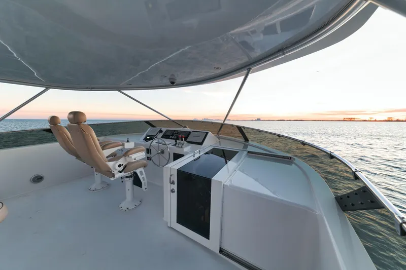 Slide: The Image of 2002 Hatteras Motor Yacht helm with dual seats, overlooking serene ocean at sunset. - 16