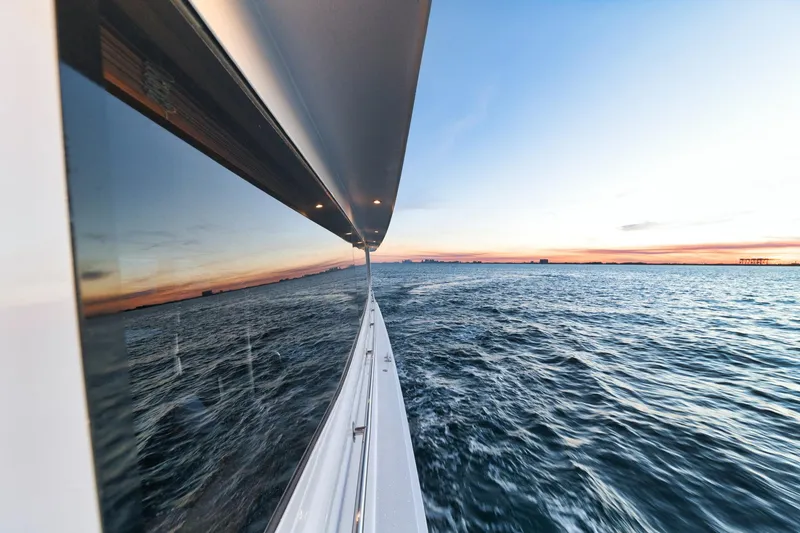 Slide: The Image of 2002 Hatteras Motor Yacht cruising at sunset, reflecting on calm ocean waters. - 24