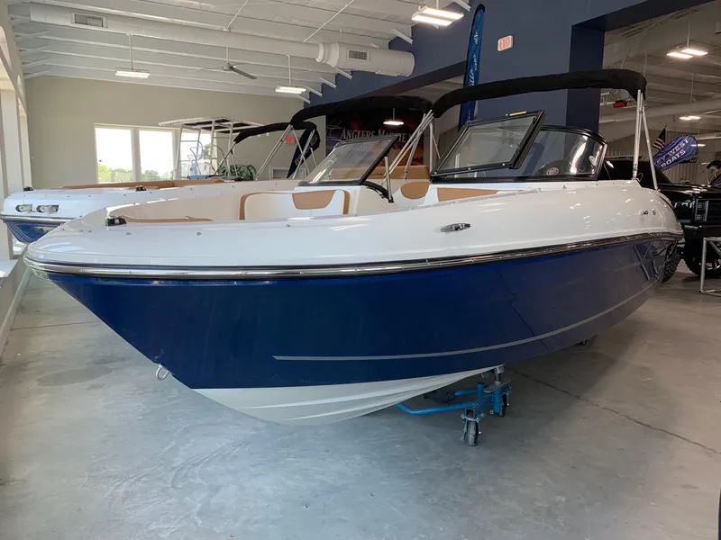 Slide: The Image of 2024 Bayliner VR4 boat in showroom, blue and white exterior, black canopy. - 2