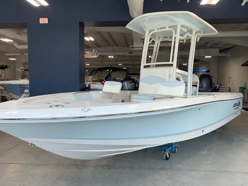Slide: The Image of 2024 Robalo 226 Cayman boat in showroom, white and light blue exterior. - 2