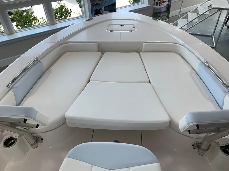 Slide: The Image of 2024 Robalo 226 Cayman boat with cushioned bow seating in showroom. - 7