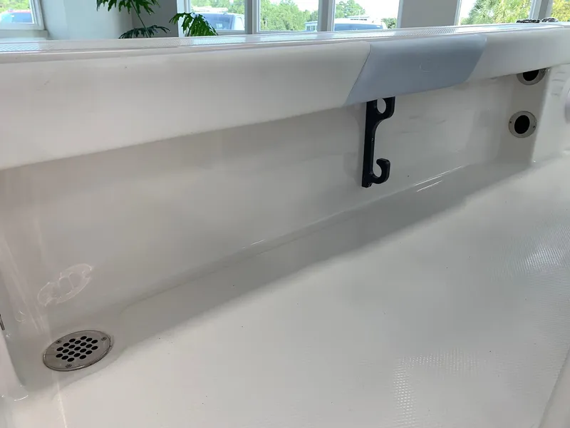 Slide: The Image of 2024 Robalo 226 Cayman boat interior detail showing storage compartment and drainage. - 14