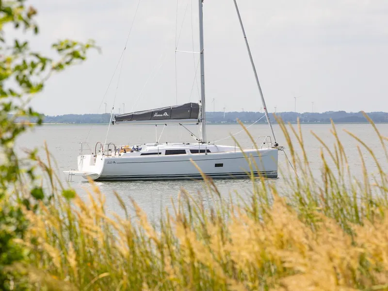 Slide: The Image of 2024 Hanse 348 sailboat on calm water, viewed through tall grass. - 23