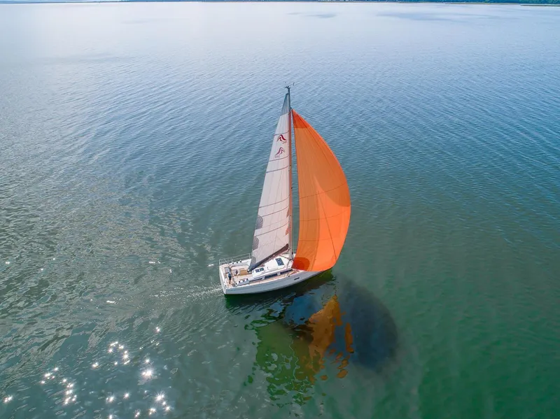 Slide: The Image of Aerial view of 2024 Hanse 348 sailboat with orange sail on calm water. - 24