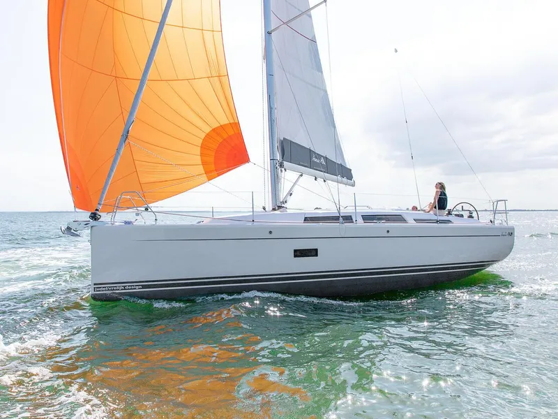 Slide: The Image of 2024 Hanse 348 sailboat with orange and gray sails on open water. - 26
