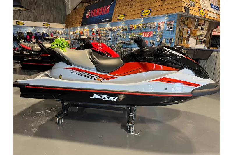 Slide: The Image of 2025 Kawasaki STX160X jet ski in showroom, featuring sleek red and black design. - 11