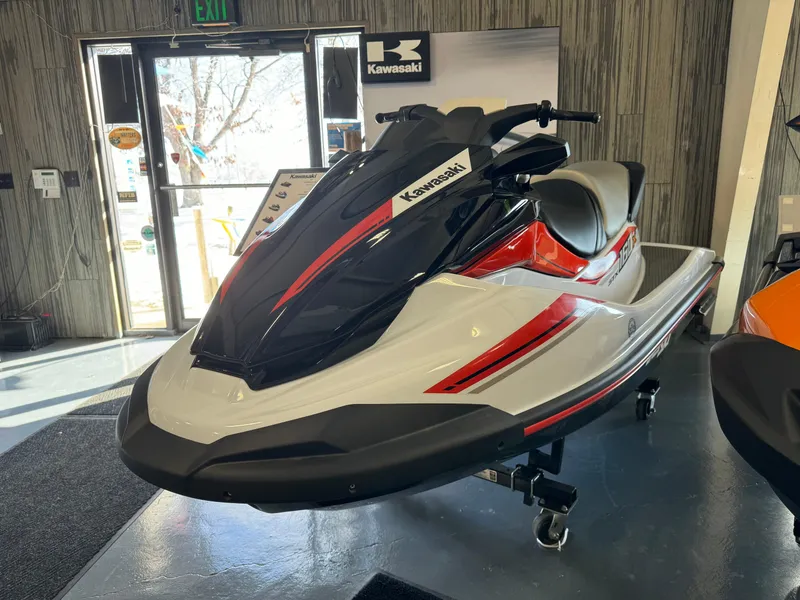 The Image of 2025 Kawasaki STX160X jet ski in showroom, featuring sleek black and red design. - 2