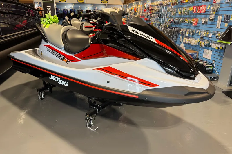Slide: The Image of 2025 Kawasaki STX160X jet ski in showroom, featuring sleek red and black design. - 4