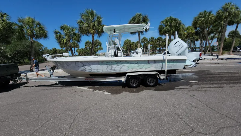 Slide: The Image of 2006 Everglades 243 CC boat on trailer, parked near palm trees under clear blue sky. - 0