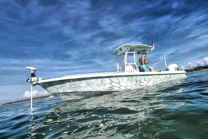 Slide: The Image of 2006 Everglades 243 CC boat on calm water with a fisherman. - 13