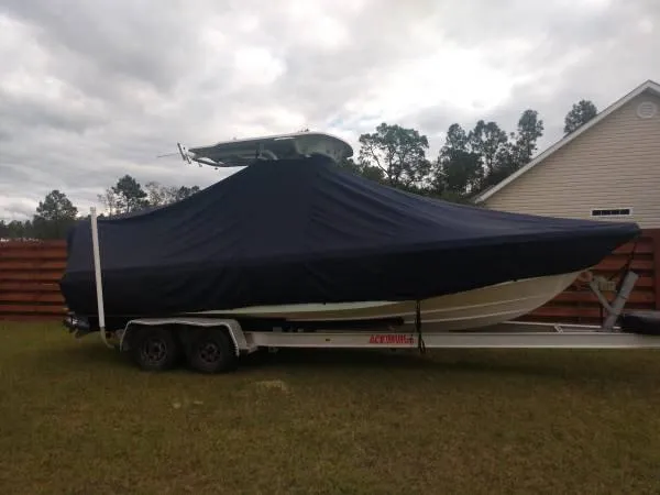 Slide: The Image of 2006 Everglades 243 CC boat covered on a trailer in a yard. - 28