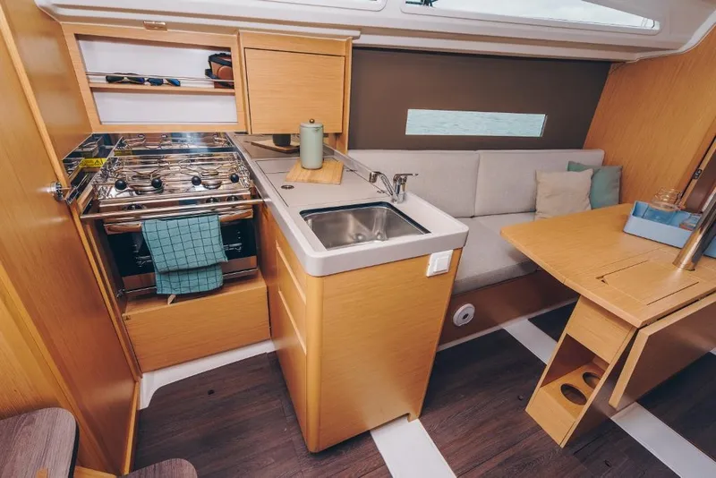 Slide: The Image of Interior of 2024 Beneteau Oceanis 30.1 yacht with modern kitchen and cozy seating area. - 2