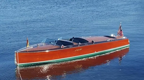 The Image of 1989 Hacker-Craft Triple Cockpit boat on calm water, showcasing classic wooden design. - 0