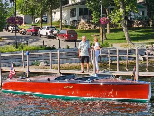 Slide: The Image of 1989 Hacker-Craft Triple Cockpit boat docked by a lakeside with two people standing nearby. - 21