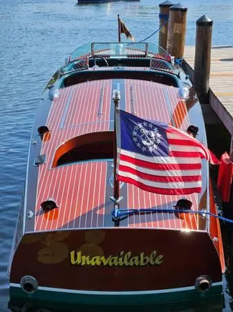 Slide: The Image of 1989 Hacker-Craft Triple Cockpit boat docked, displaying a vintage American flag. - 33