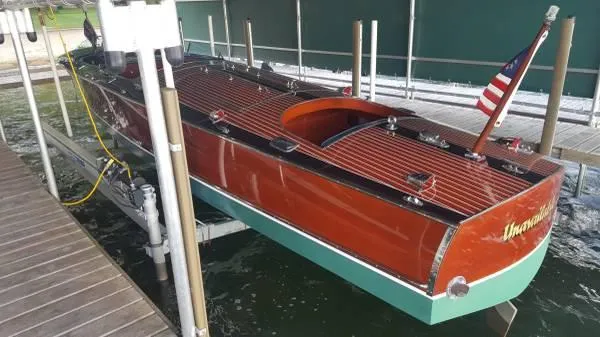 Slide: The Image of 1989 Hacker-Craft Triple Cockpit boat docked, showcasing classic wooden design and American flag. - 7