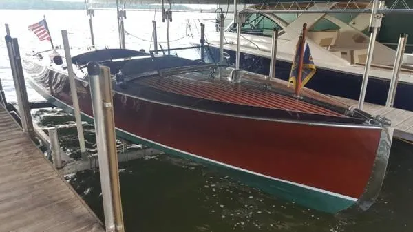 Slide: The Image of 1989 Hacker-Craft Triple Cockpit boat docked, showcasing classic wooden design and American flag. - 8