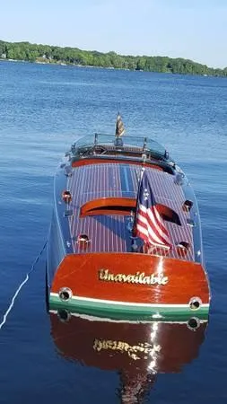 Slide: The Image of 1989 Hacker-Craft Triple Cockpit boat on a serene lake with American flag. - 9