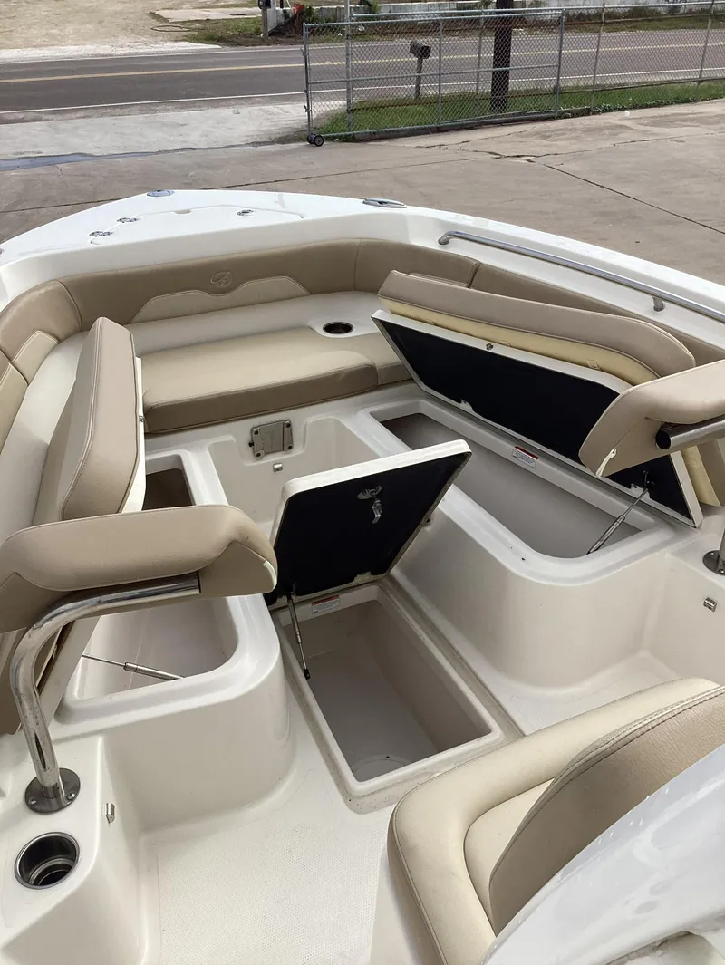 Slide: The Image of 2021 Sailfish 241CC boat interior with open storage compartments and beige seating. - 10
