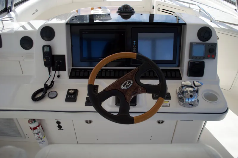 Slide: The Image of 2005 Sea Ray 550 Sedan Bridge helm with dual screens and wooden steering wheel. - 16