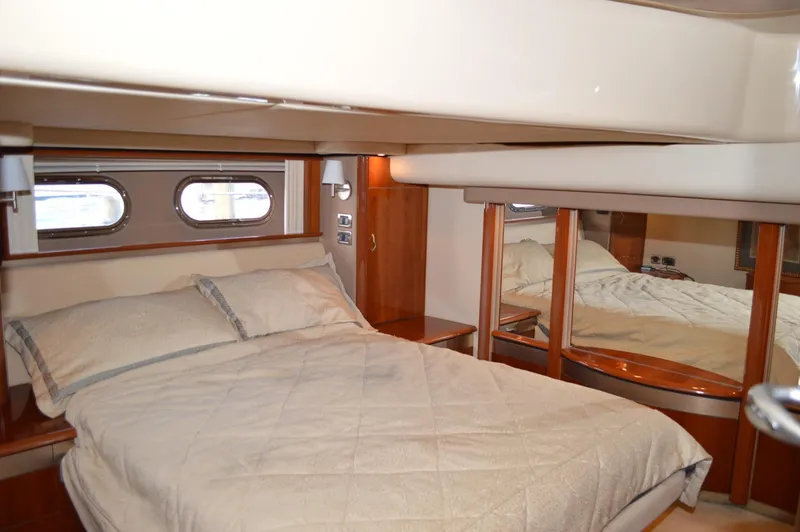 Slide: The Image of Luxurious bedroom interior of 2005 Sea Ray 550 Sedan Bridge yacht with double bed and porthole windows. - 8