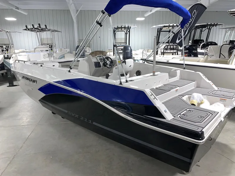 Slide: The Image of 2024 Starcraft SVX 211 boat in showroom, blue and white design, modern interior. - 2