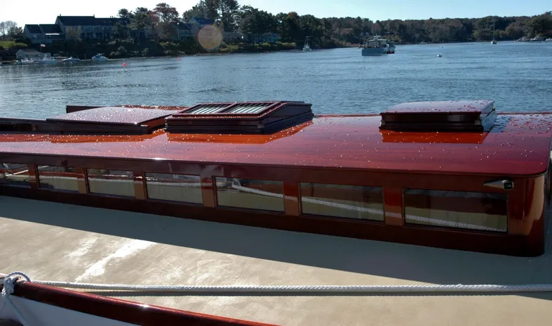 Slide: The Image of Historic 1902 Herreshoff Gaff Cutter yacht on tranquil water, showcasing elegant wooden craftsmanship. - 10