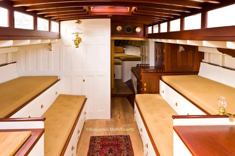 Slide: The Image of Interior of a 1902 Herreshoff Gaff Cutter, featuring classic wooden design and cozy seating. - 12