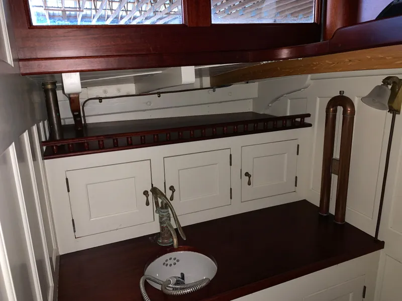 Slide: The Image of Interior of 1902 Herreshoff Gaff Cutter, featuring vintage cabinetry and sink. - 16