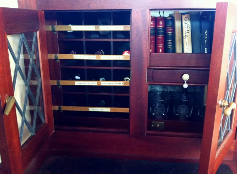 Slide: The Image of Antique wooden cabinet with glass doors, housing books and wine bottles, Herreshoff Gaff Cutter 1902. - 19