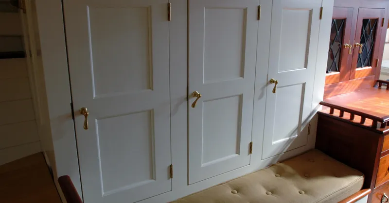 Slide: The Image of Interior of 1902 Herreshoff Gaff Cutter with white cabinets and cushioned seating. - 24