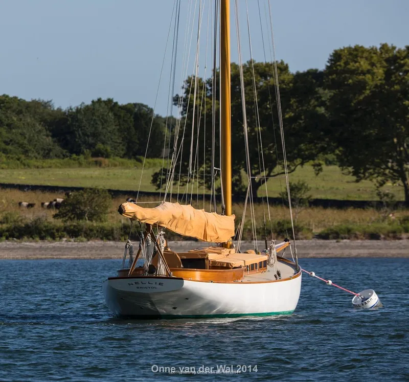 Slide: The Image of Vintage 1902 Herreshoff Gaff Cutter sailboat anchored on calm water. - 5