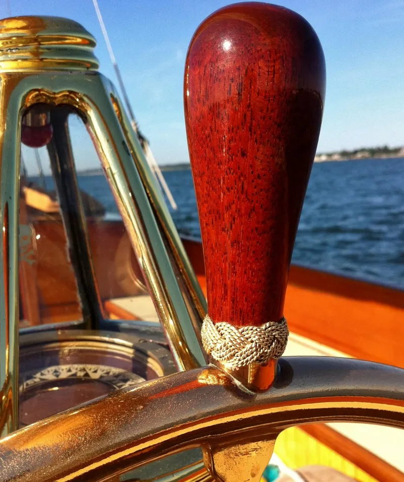 Slide: The Image of Close-up of a 1902 Herreshoff Gaff Cutter's polished wooden helm on open water. - 9